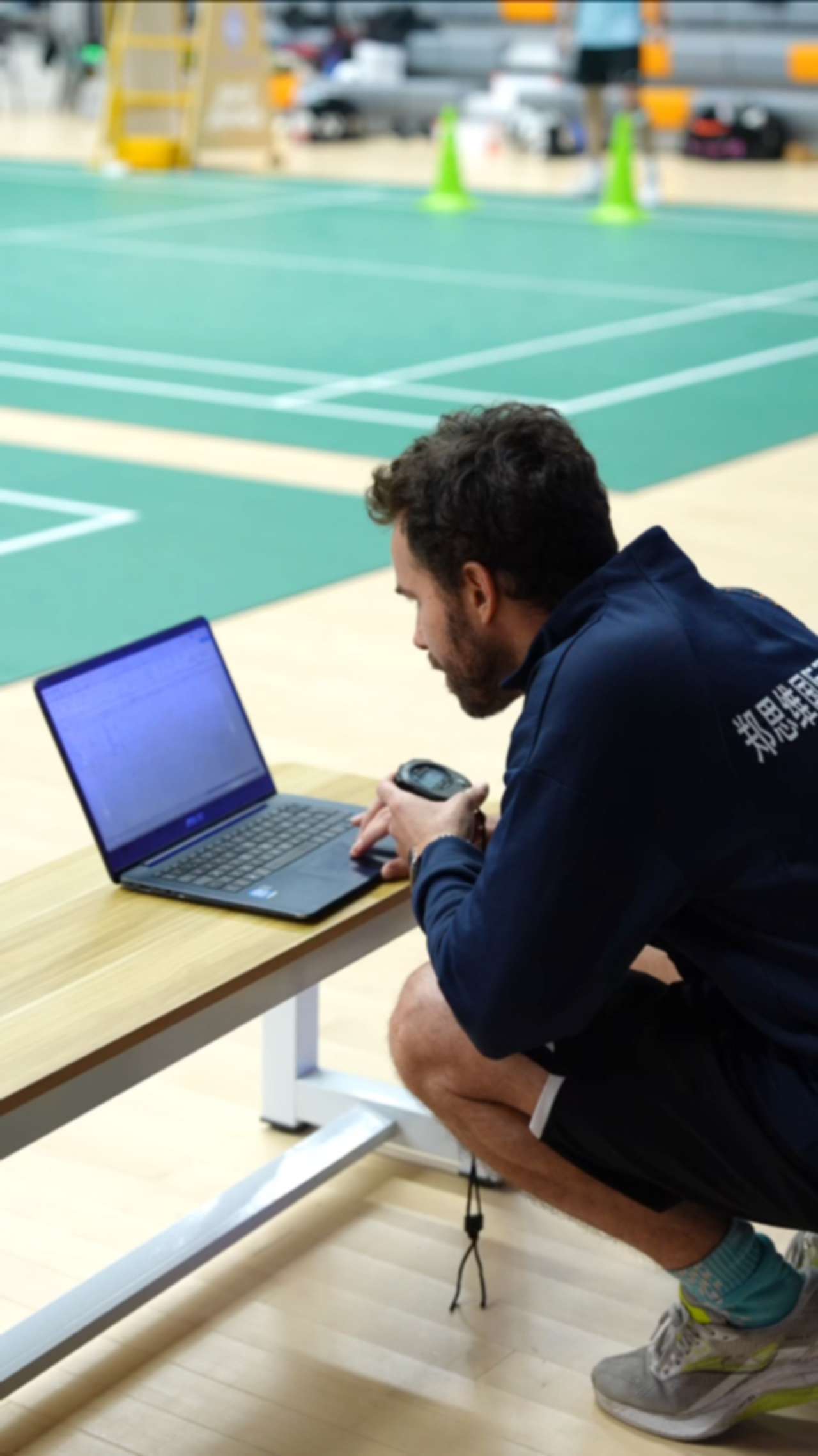 Cristian Luque analysing badminton performance data courtside during athlete coaching